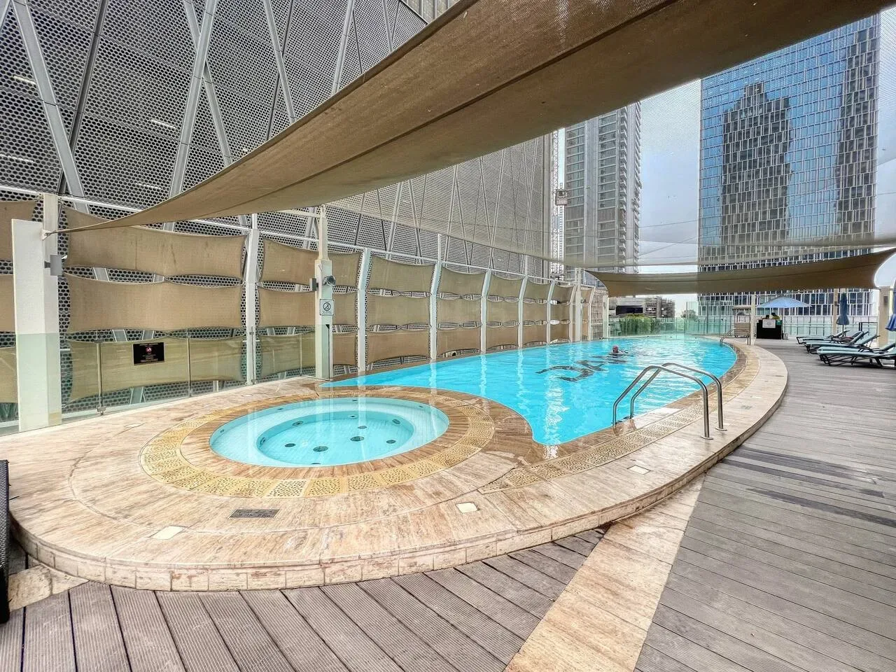 A rooftop pool and circular spa sit beside a wooden deck.