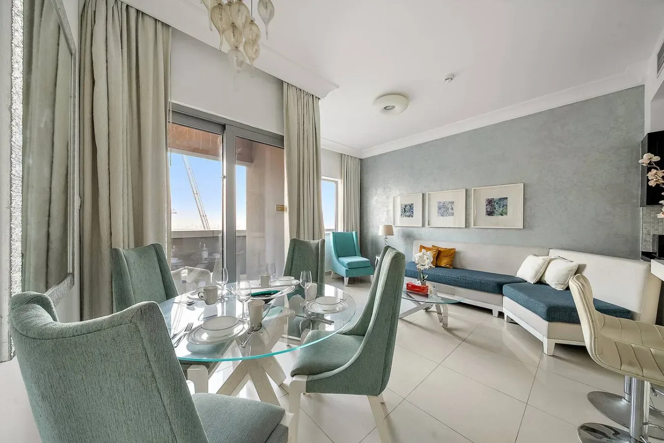 A bright living and dining area with a glass table and seating beside tall windows.