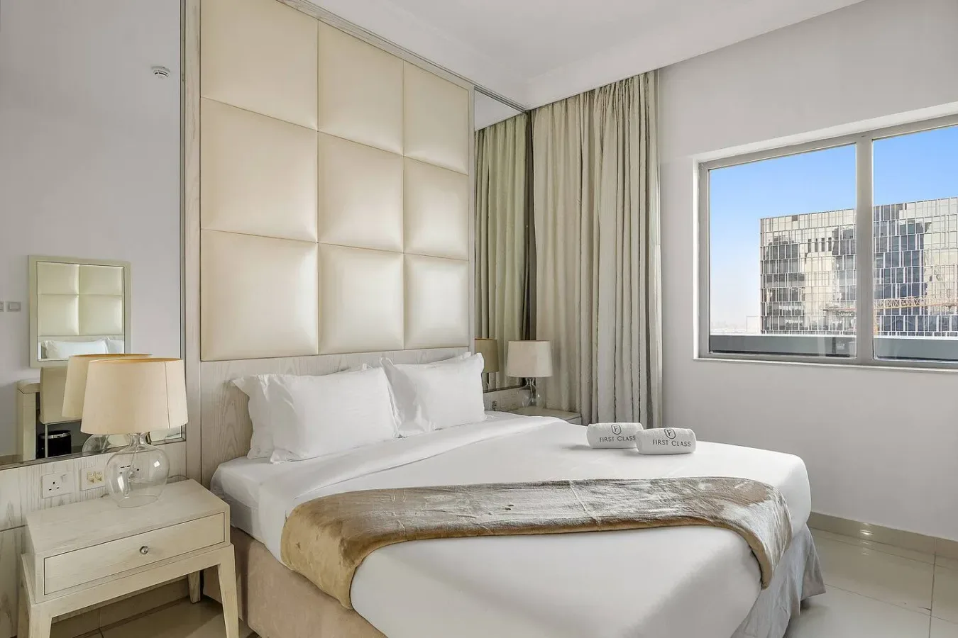 A bright bedroom with a large bed beside a wide window.