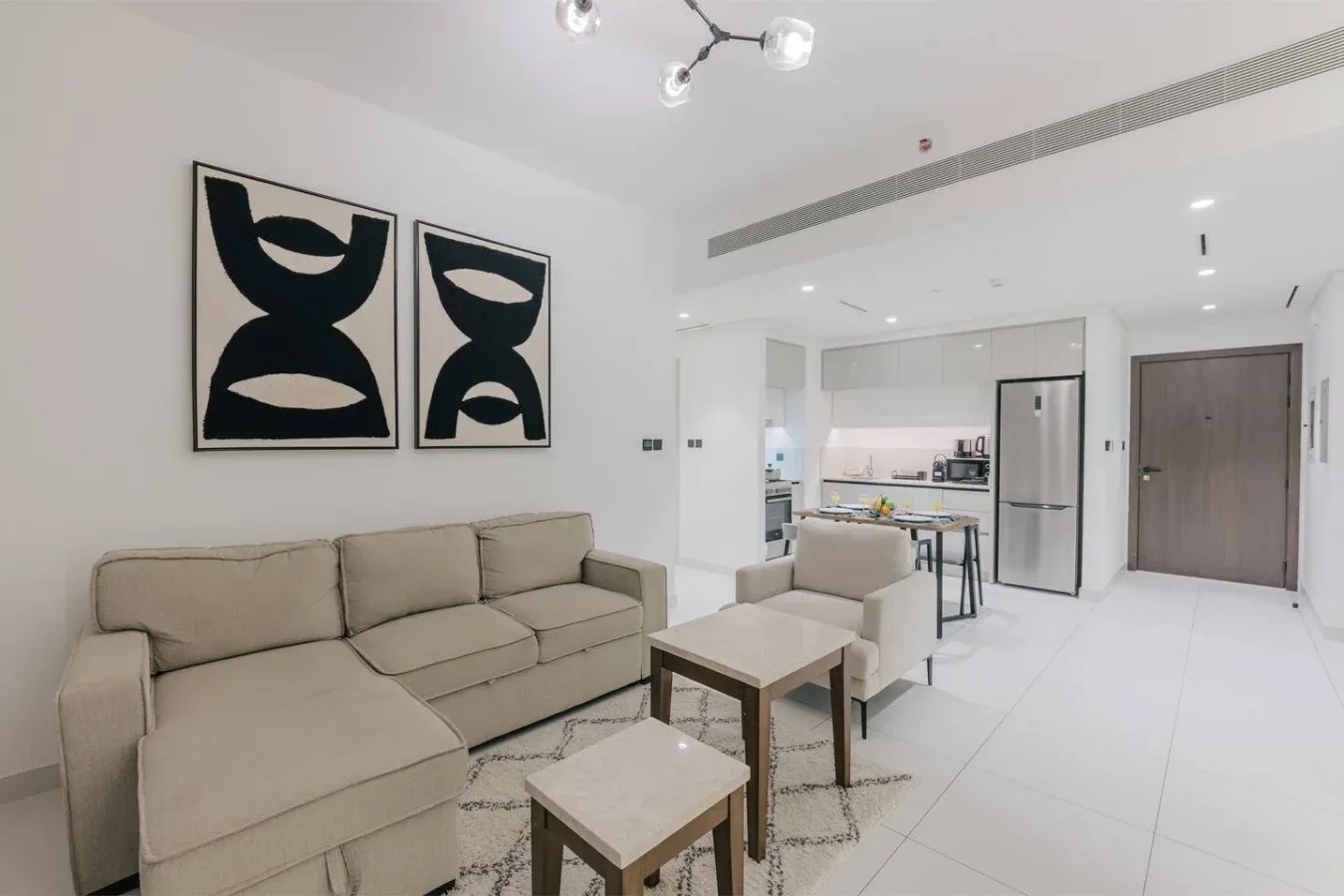 Una luminosa sala de estar diáfana con asientos, una mesa de centro y una zona de cocina.