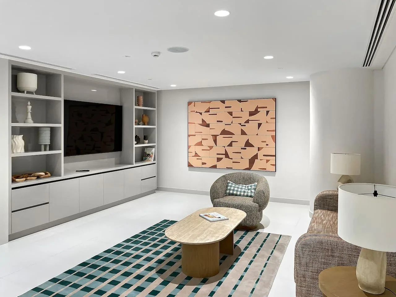 Una sala de estar moderna con televisor, alfombra estampada y arte abstracto en la pared.