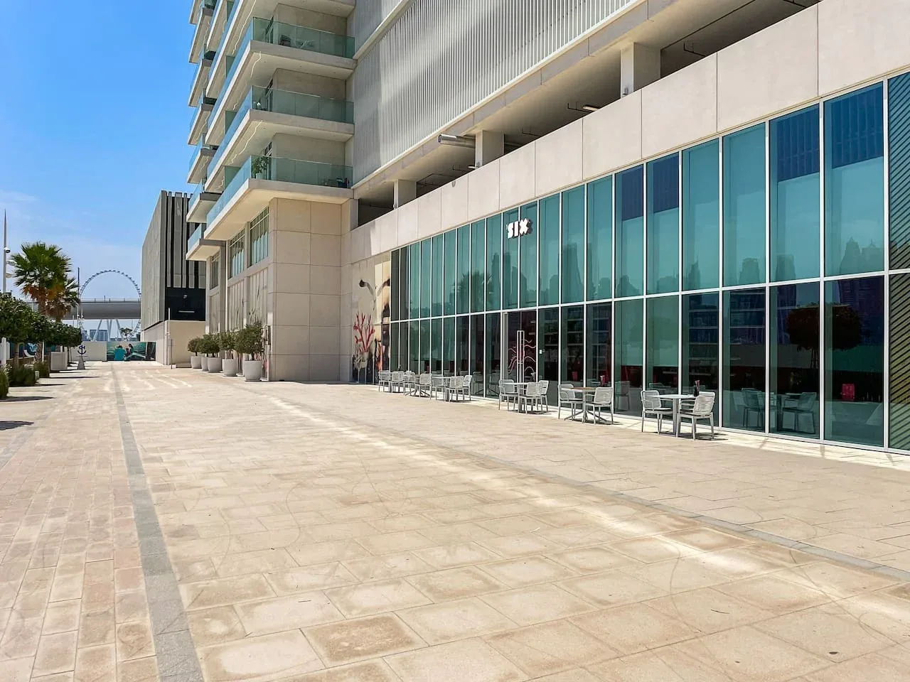 Un paseo exterior pavimentado junto a un edificio moderno con grandes ventanales.