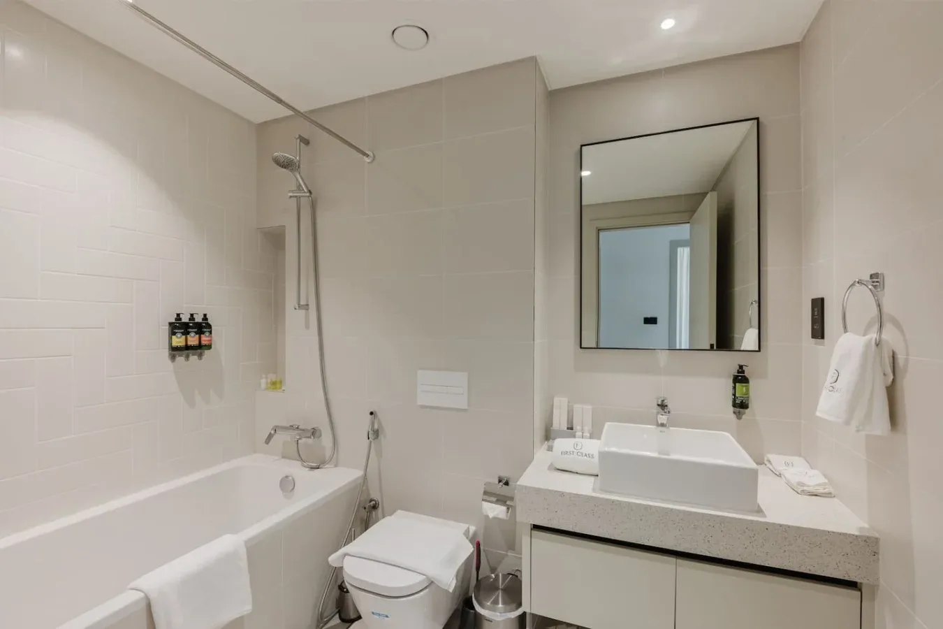 Un baño con bañera, ducha y lavabo bajo un espejo grande.