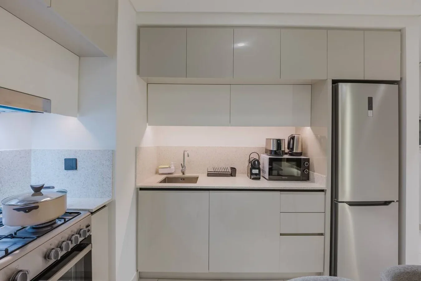 Una cocina moderna con gabinetes claros, una encimera y electrodomésticos de acero inoxidable.