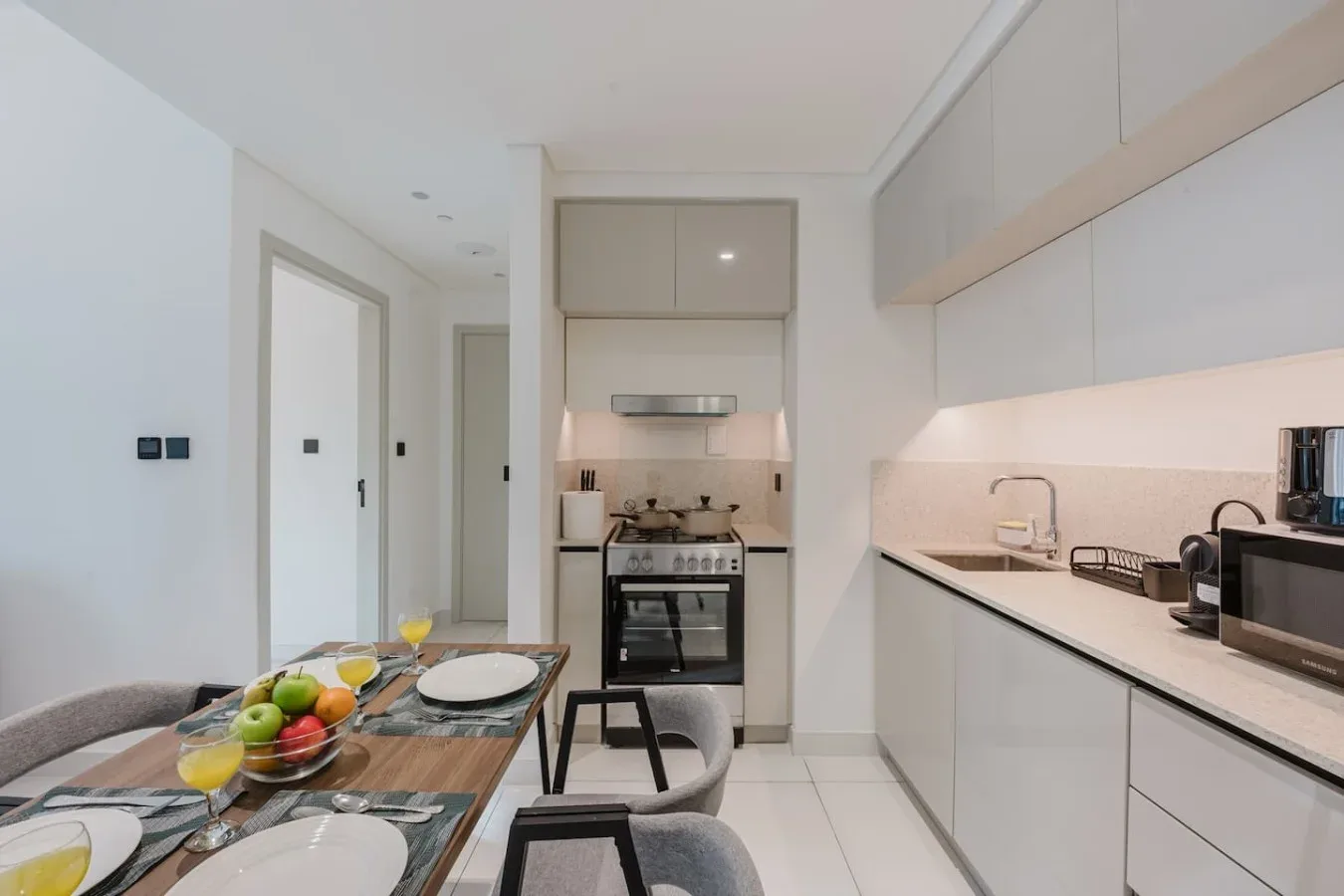 Cocina y comedor modernos con una mesa puesta con platos y fruta.