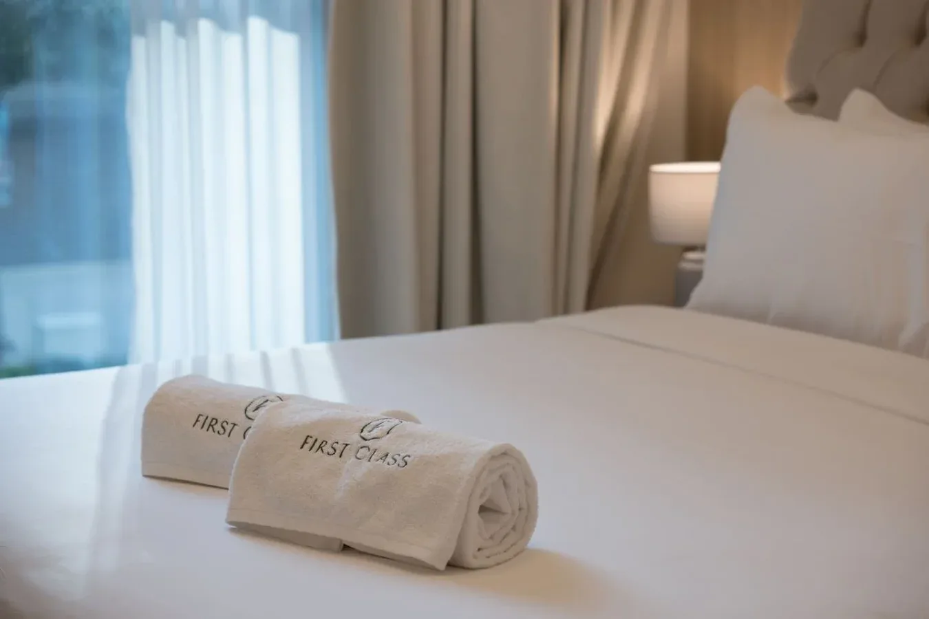 Un dormitorio con una cama bien hecha y toallas dobladas cerca de los pies.