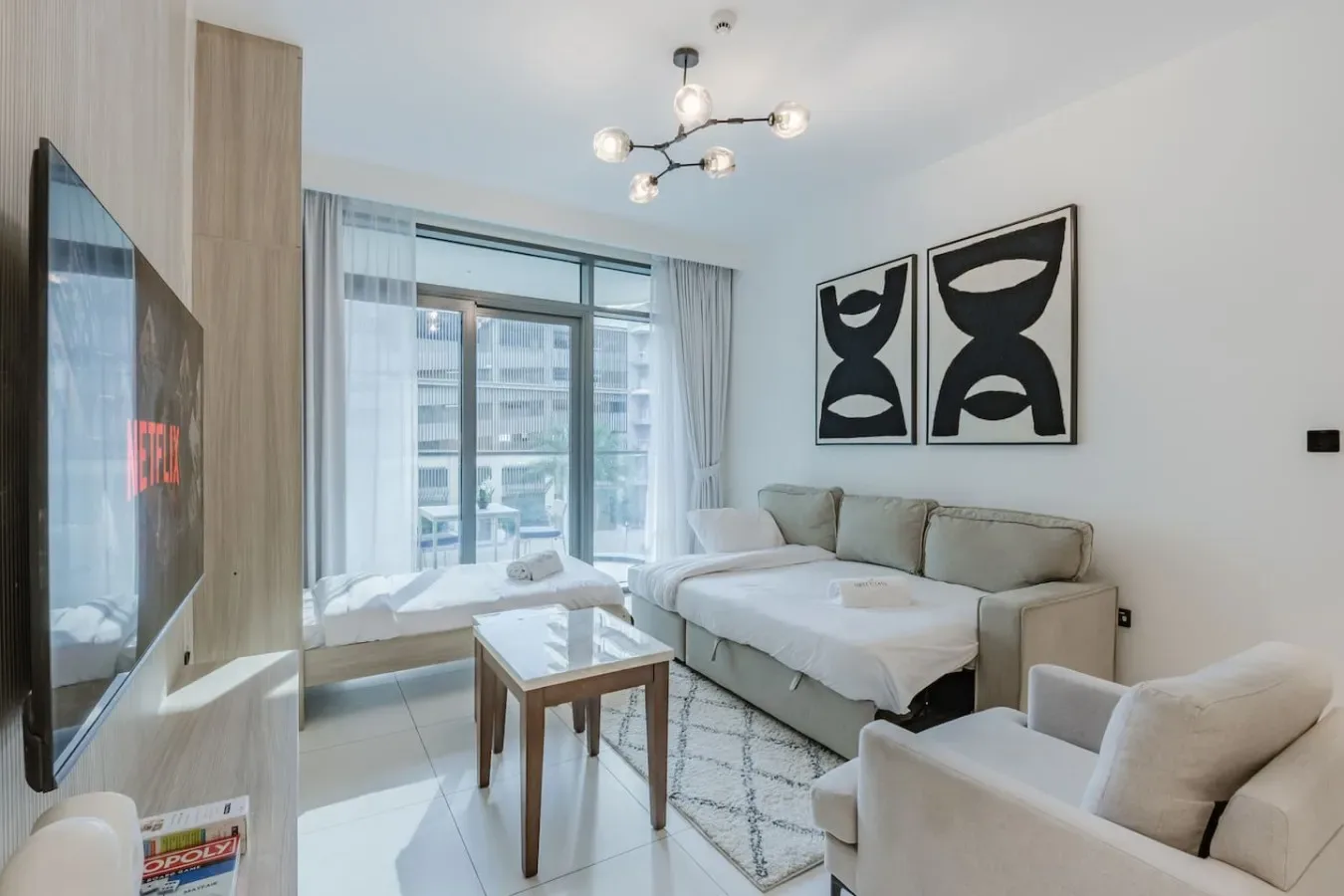 Una sala luminosa con sofá seccional, sillón y grandes ventanales.