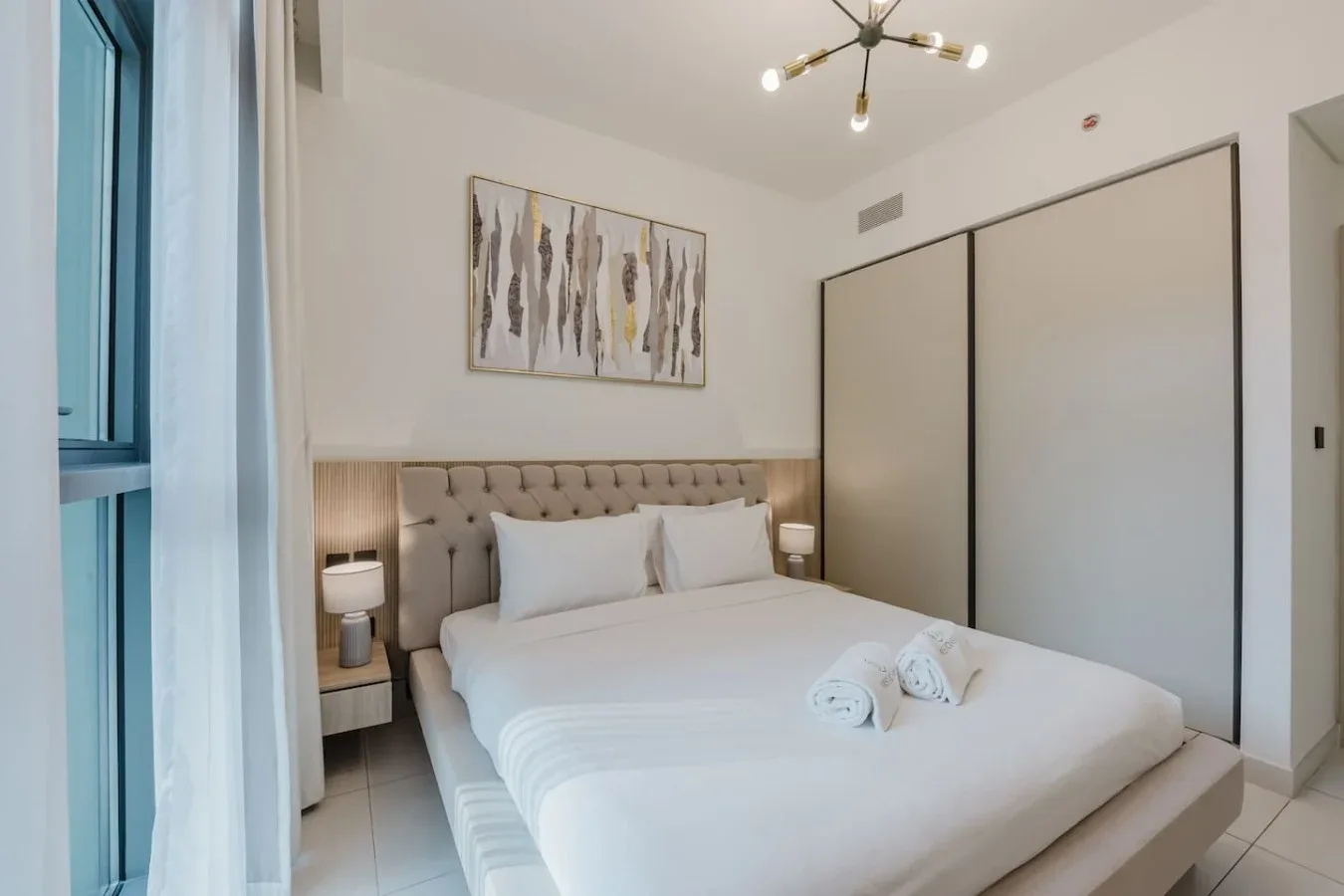 Un dormitorio con la cama tendida y una obra abstracta sobre el cabecero.