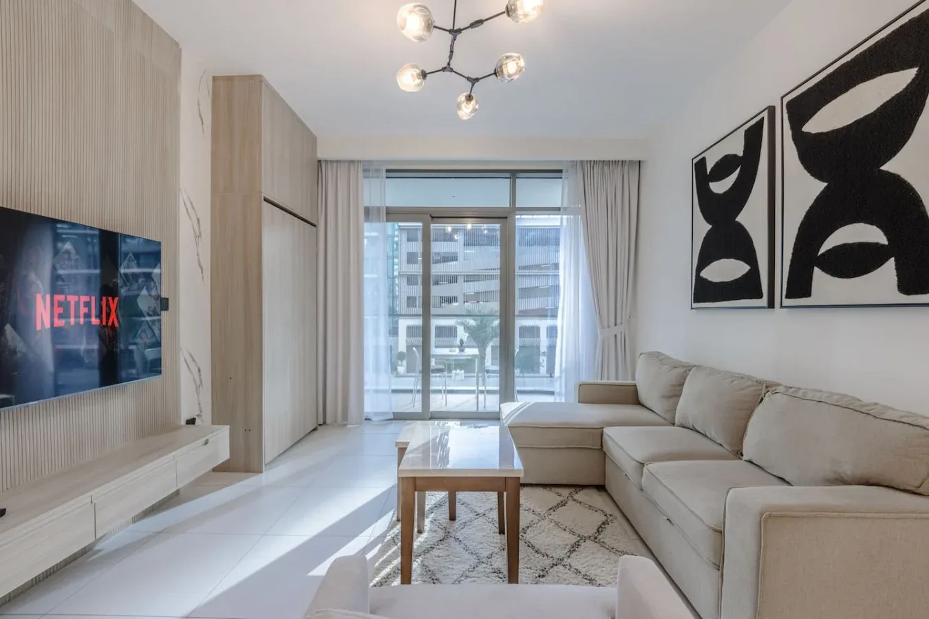 Una sala luminosa con asientos en L, una mesa de centro y un televisor en la pared.