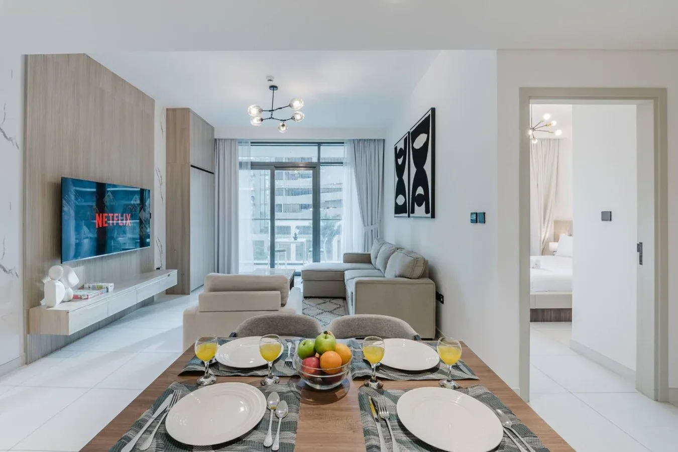 Una luminosa sala de estar y comedor con la mesa puesta y grandes ventanas.