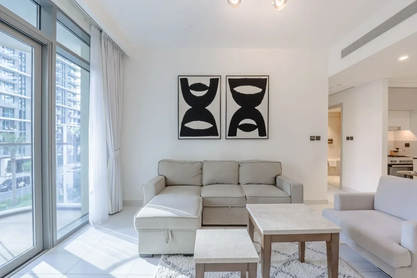 Una sala luminosa con un sofá seccional y dos cuadros enmarcados.