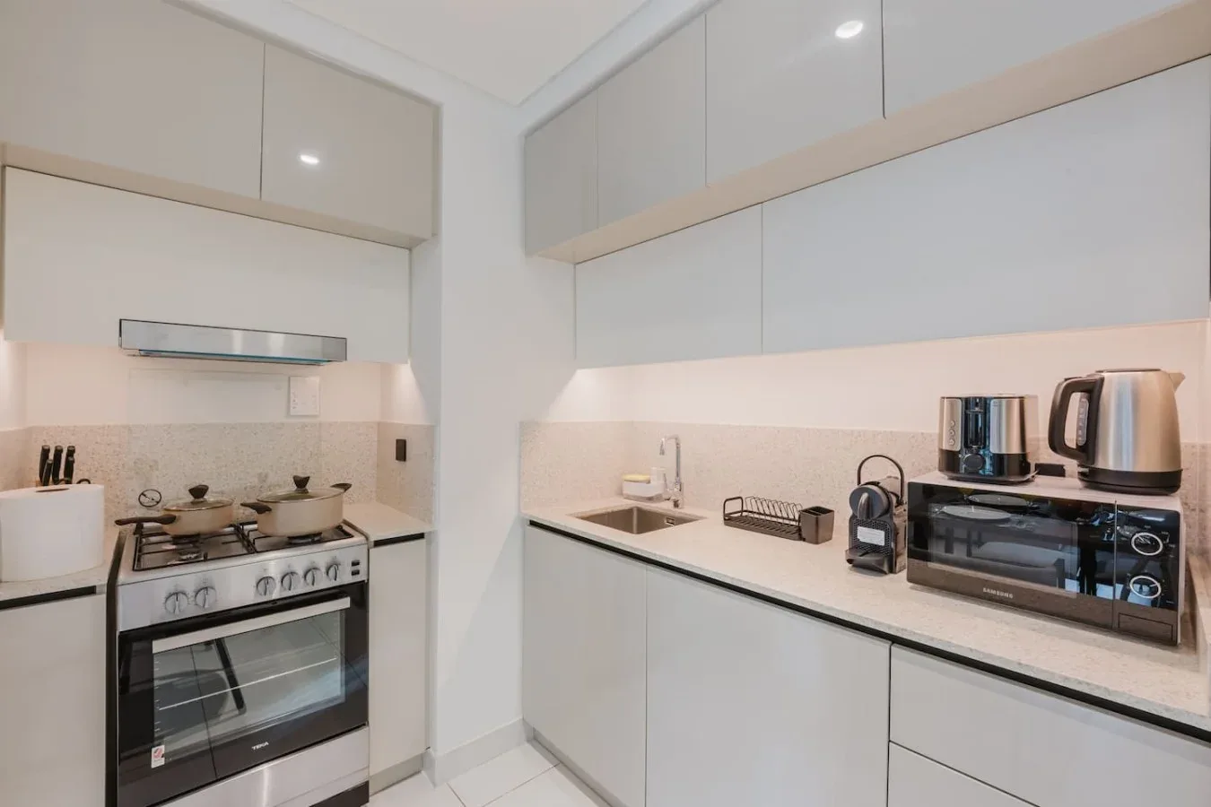 Una cocina compacta con gabinetes claros, una estufa y electrodomésticos sobre la encimera.
