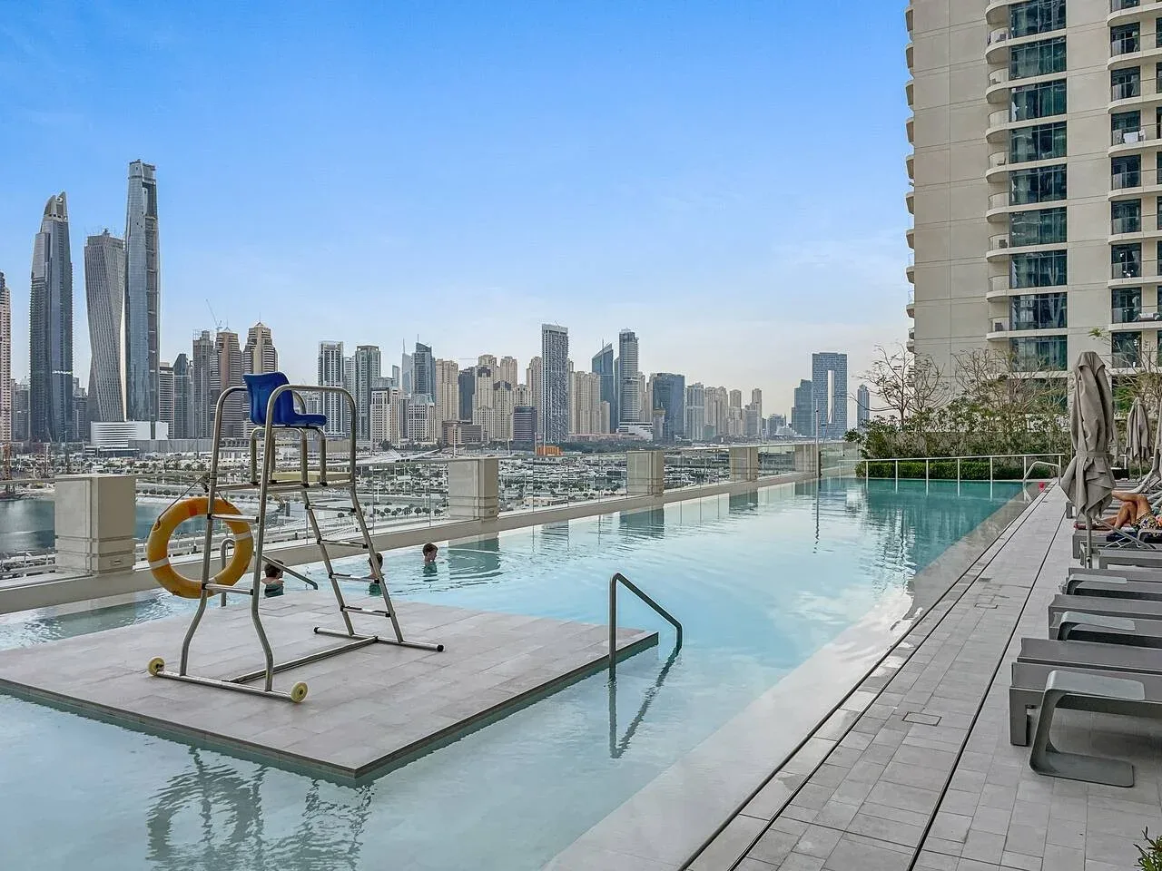 Una piscina en la azotea ofrece vistas al perfil urbano, con asientos junto a la terraza.