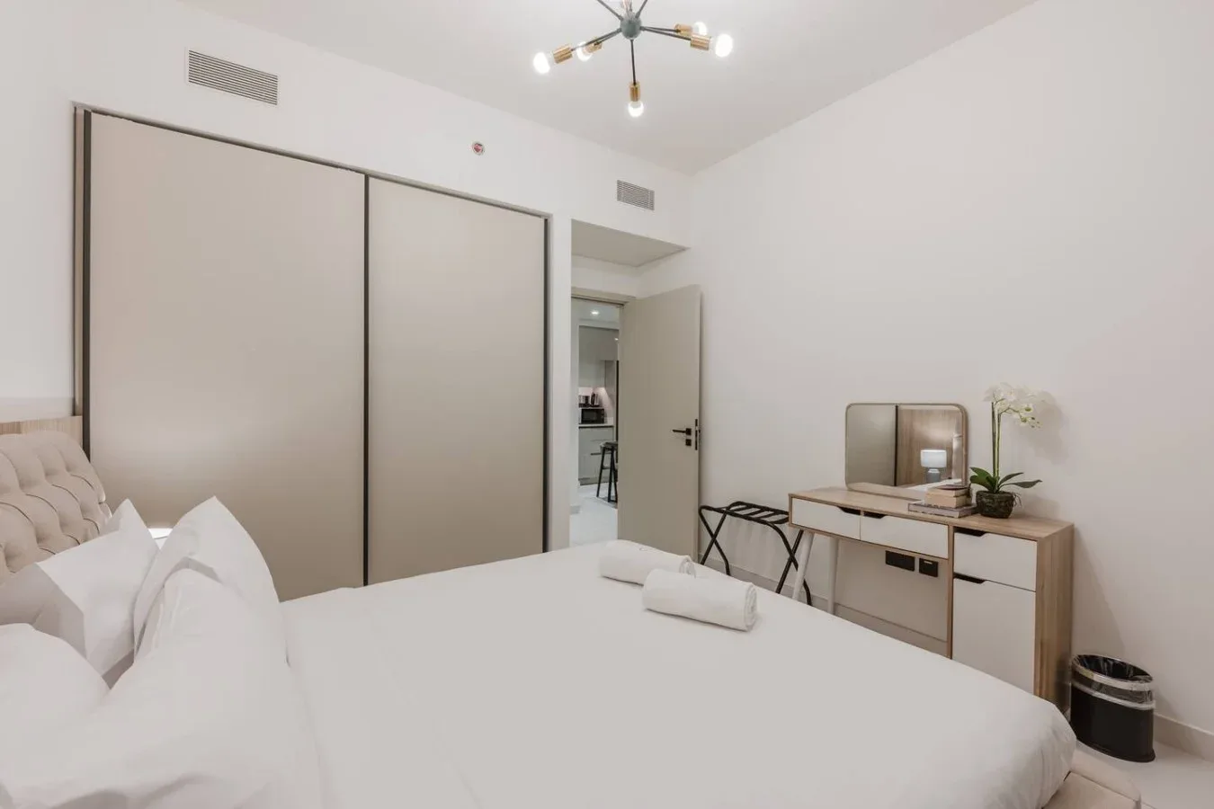 Un dormitorio luminoso con una cama grande, armarios empotrados y un escritorio pequeño.