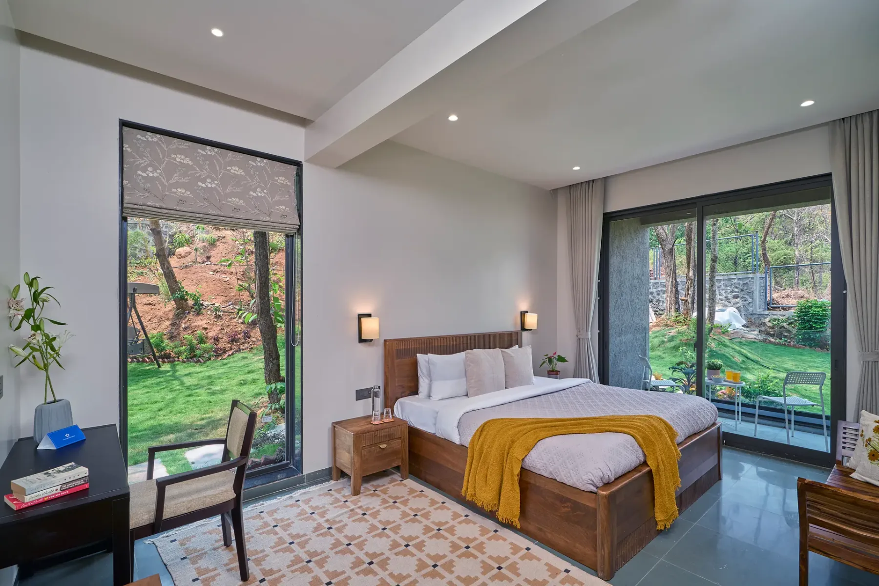 Un dormitorio con una cama y grandes ventanales con vistas a un jardín.