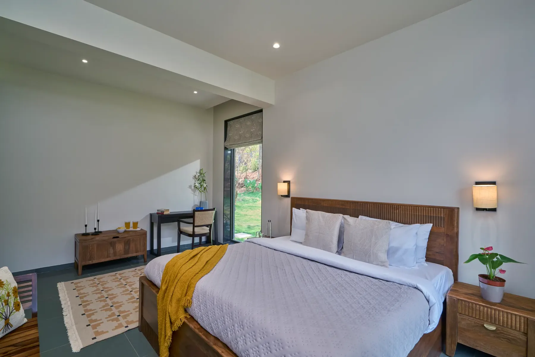 Un dormitorio con una cama grande, mesitas de noche y una ventana con vista a la vegetación.