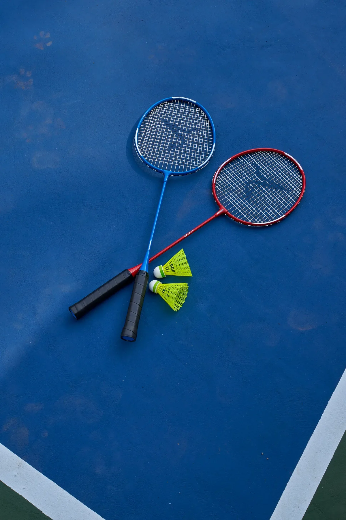 Dos raquetas de bádminton y volantes están sobre una pista azul.