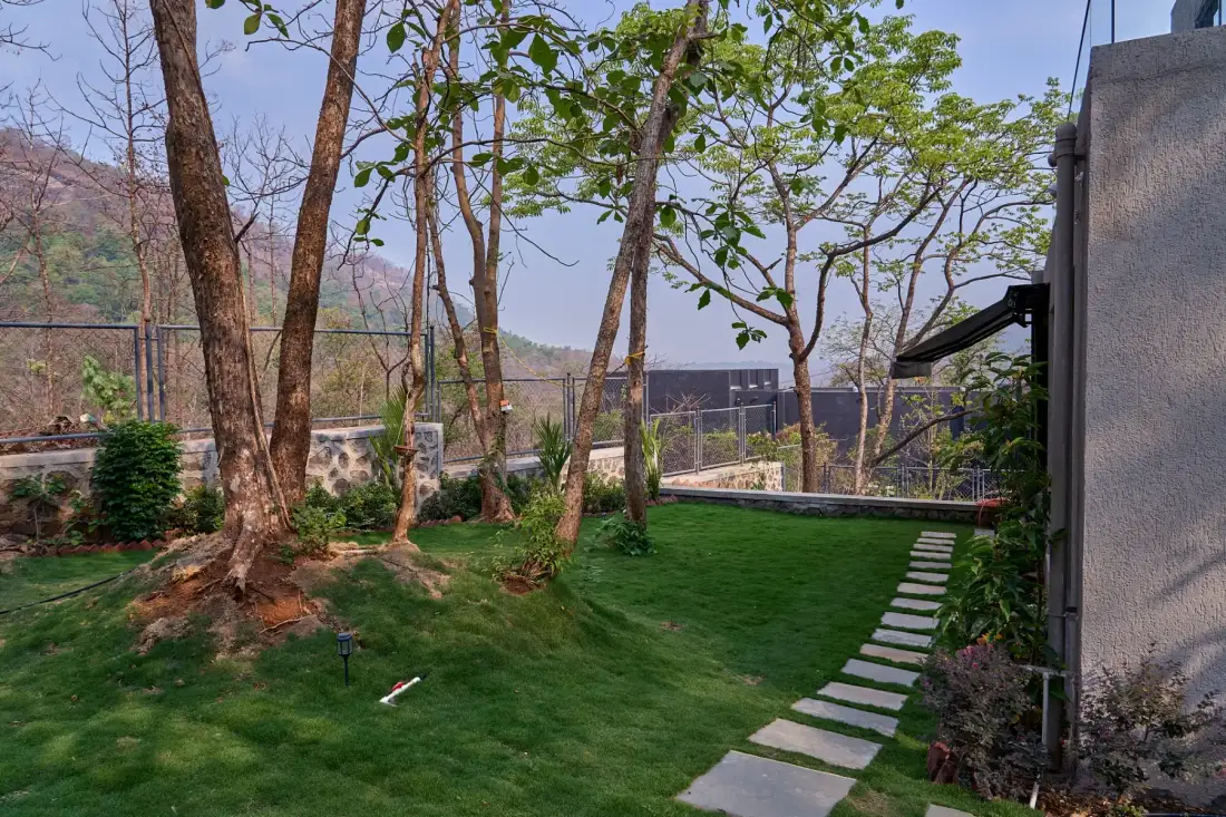 Un jardín ajardinado con piedras para caminar, árboles y una vista cercada.