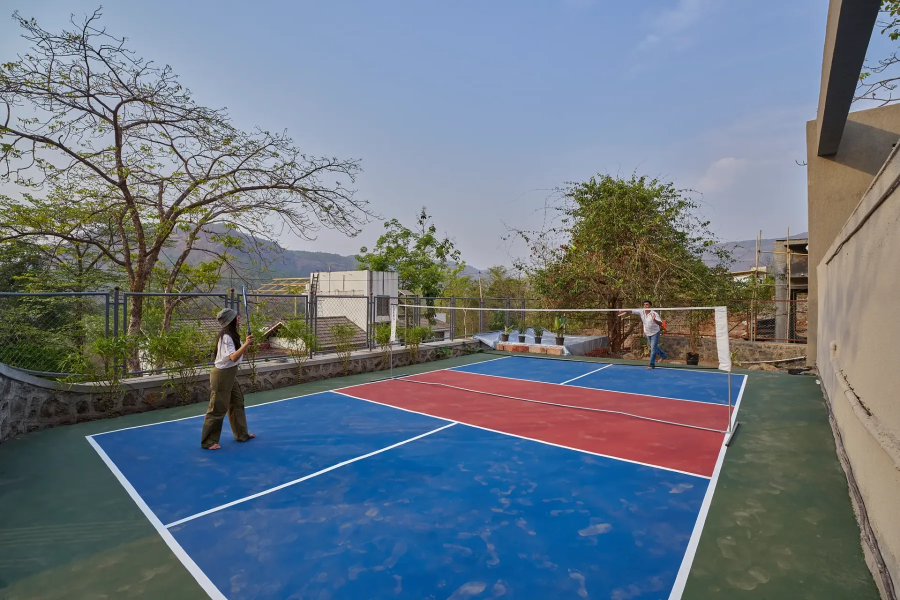 Una cancha deportiva al aire libre con superficies de juego azules y rojas y dos personas.