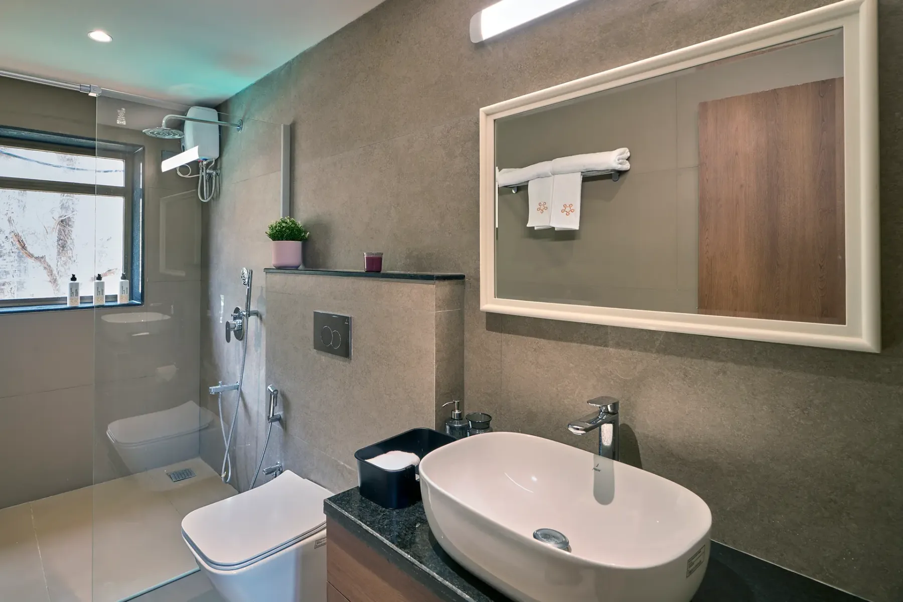 Un baño moderno con un espejo grande y un lavabo sobre encimera.