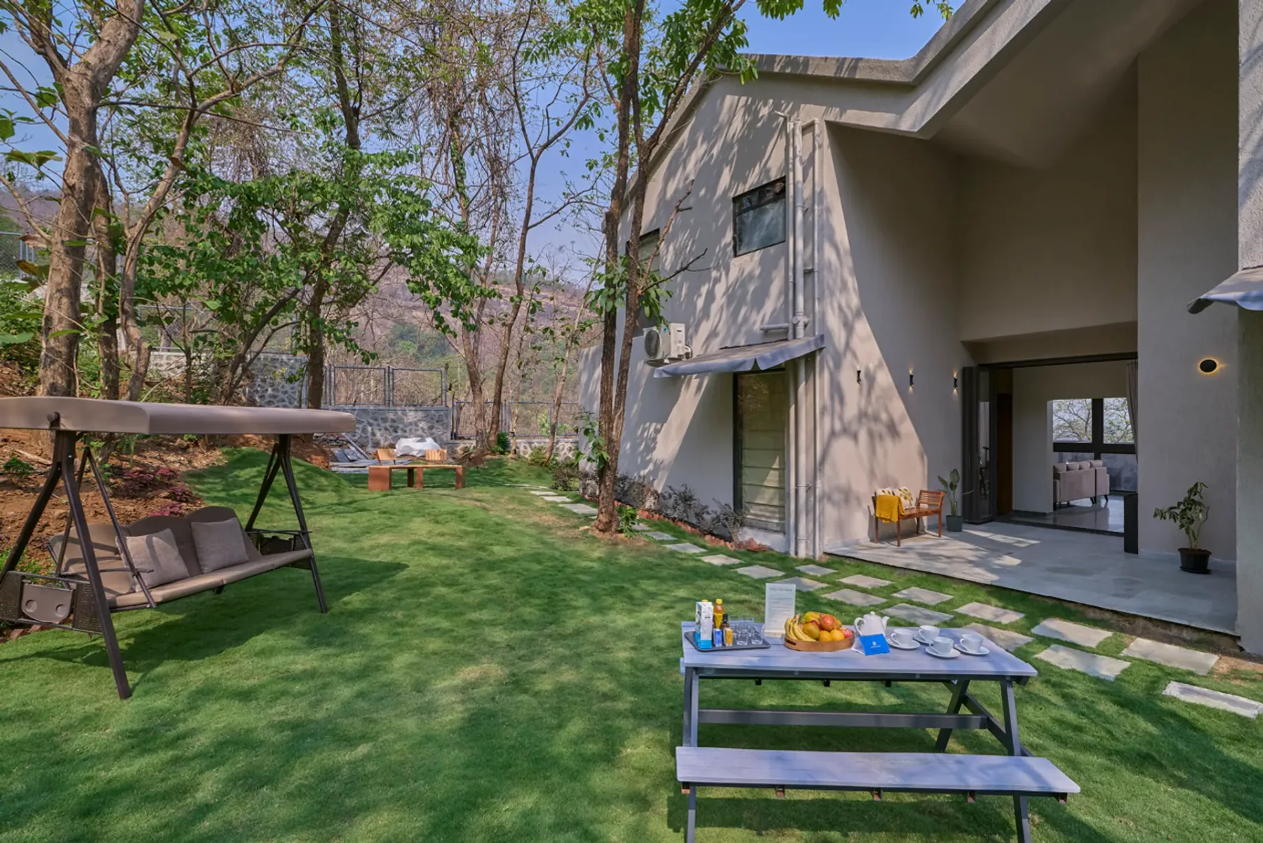 Una casa moderna da a un césped con asientos al aire libre y una mesa baja.