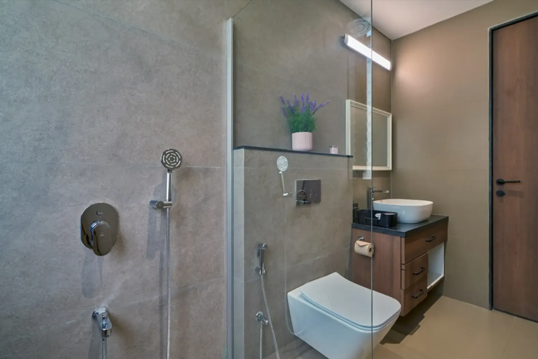 Un baño moderno con ducha de vidrio, inodoro suspendido y lavabo.