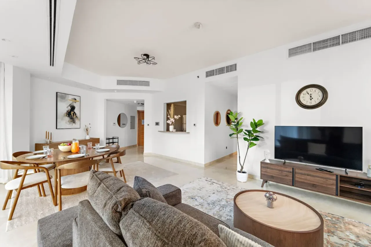 Una luminosa sala de estar y comedor con sofá, televisor y mesa de comedor.