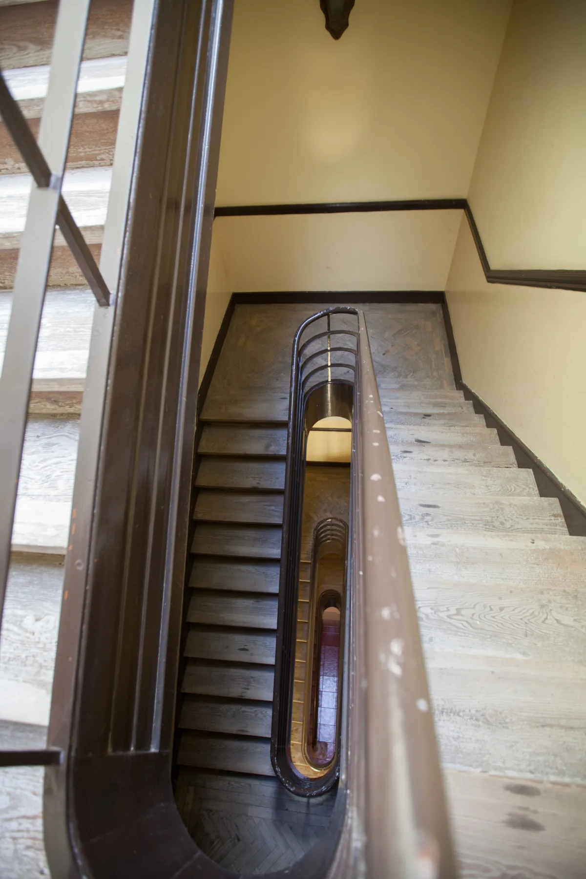 A stairwell with a central wooden handrail and steps on either side.