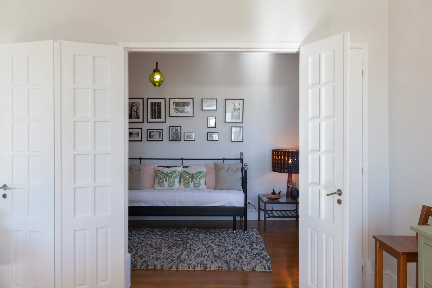 A bedroom with a bed, framed pictures, and a patterned rug.