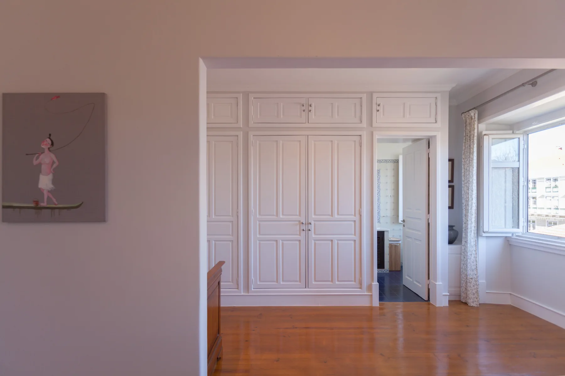 A bright bedroom with built-in cabinets and a large window.