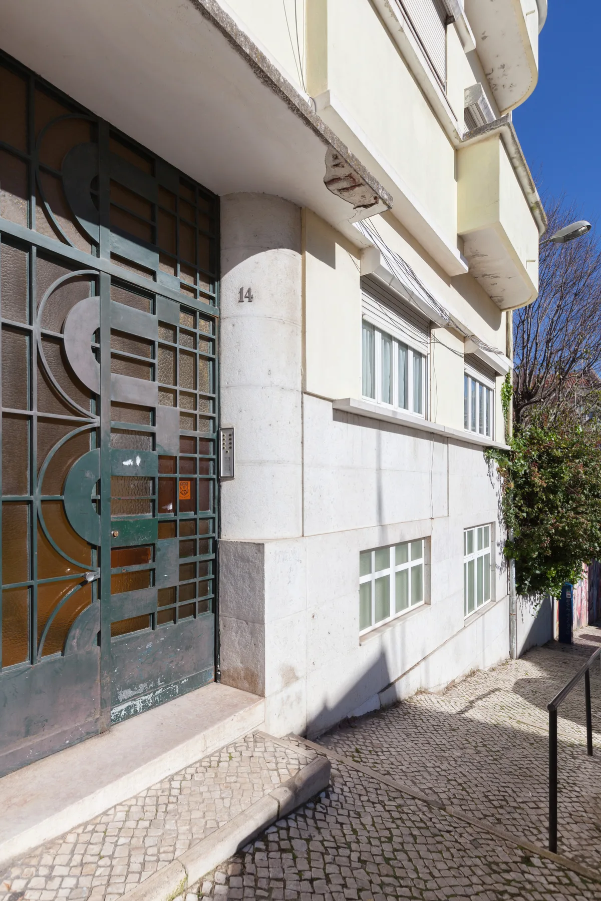 A building entrance opens onto a cobblestone sidewalk beside a pale facade.