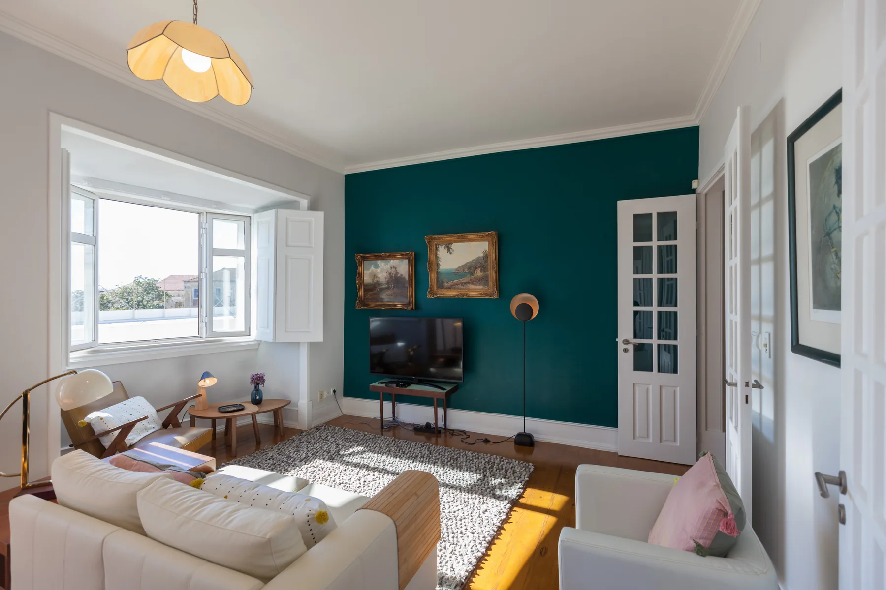 A living room with seating, a television, and a large window.