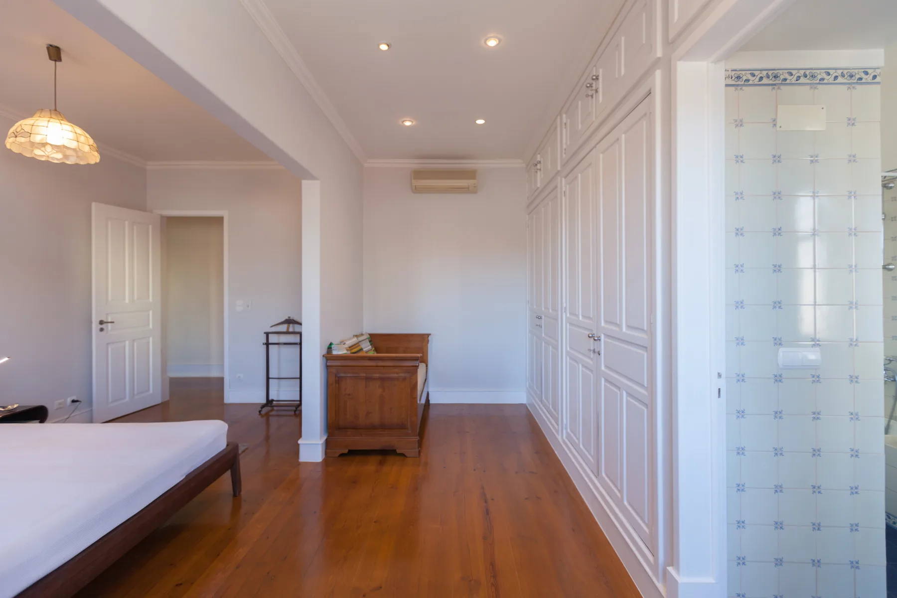 A bright bedroom with wooden flooring and built-in wardrobes.