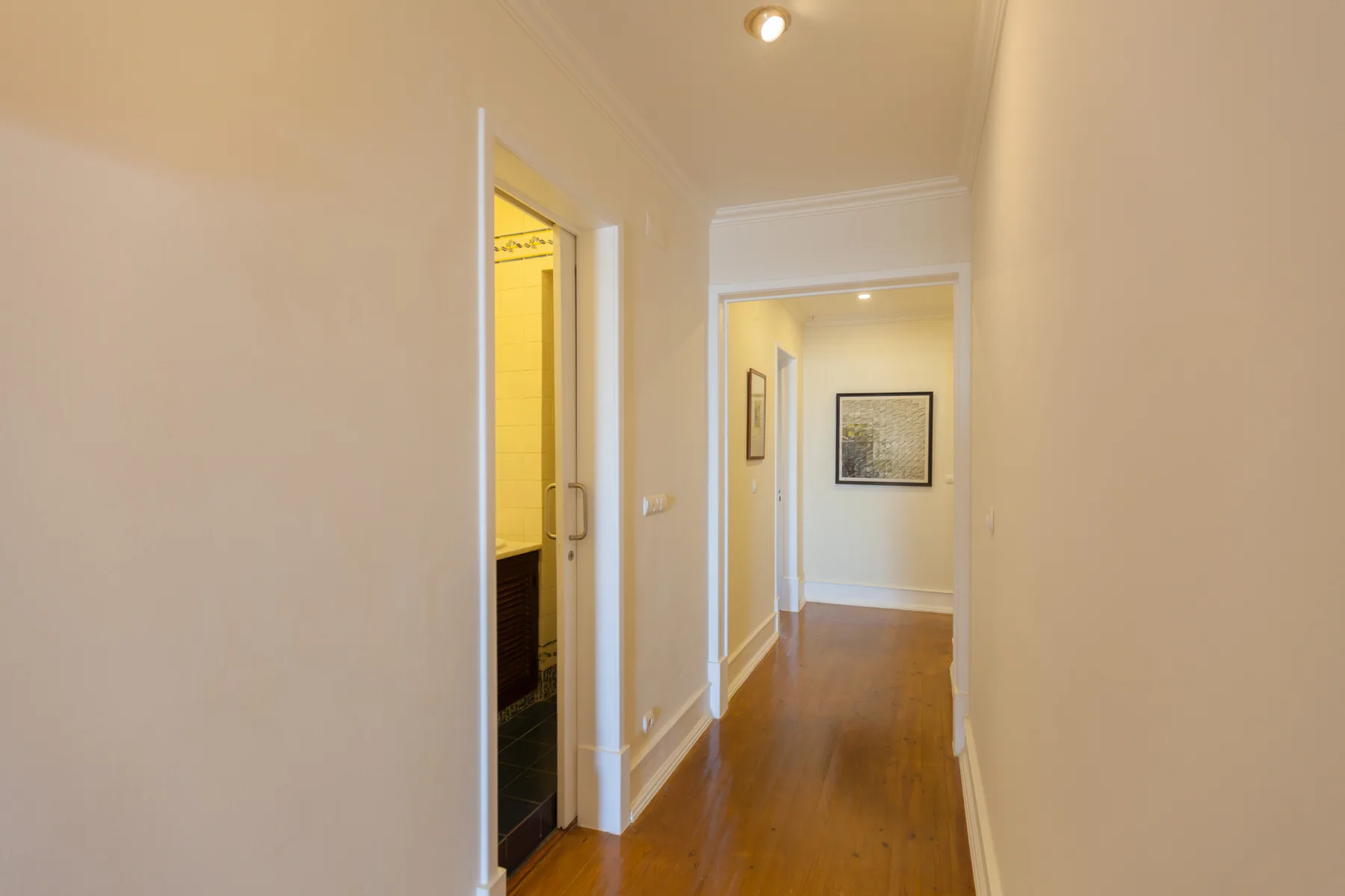 A hallway with wooden flooring and several open doorways.