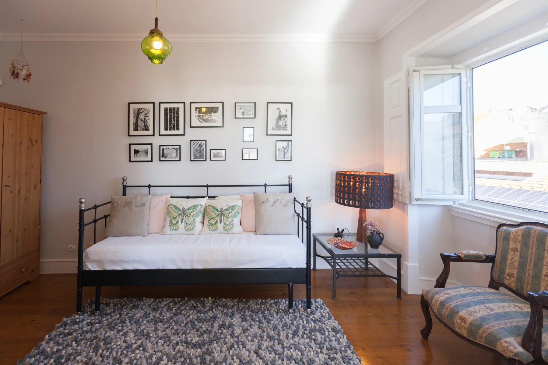 A bedroom with a bed, framed pictures, and a large window.