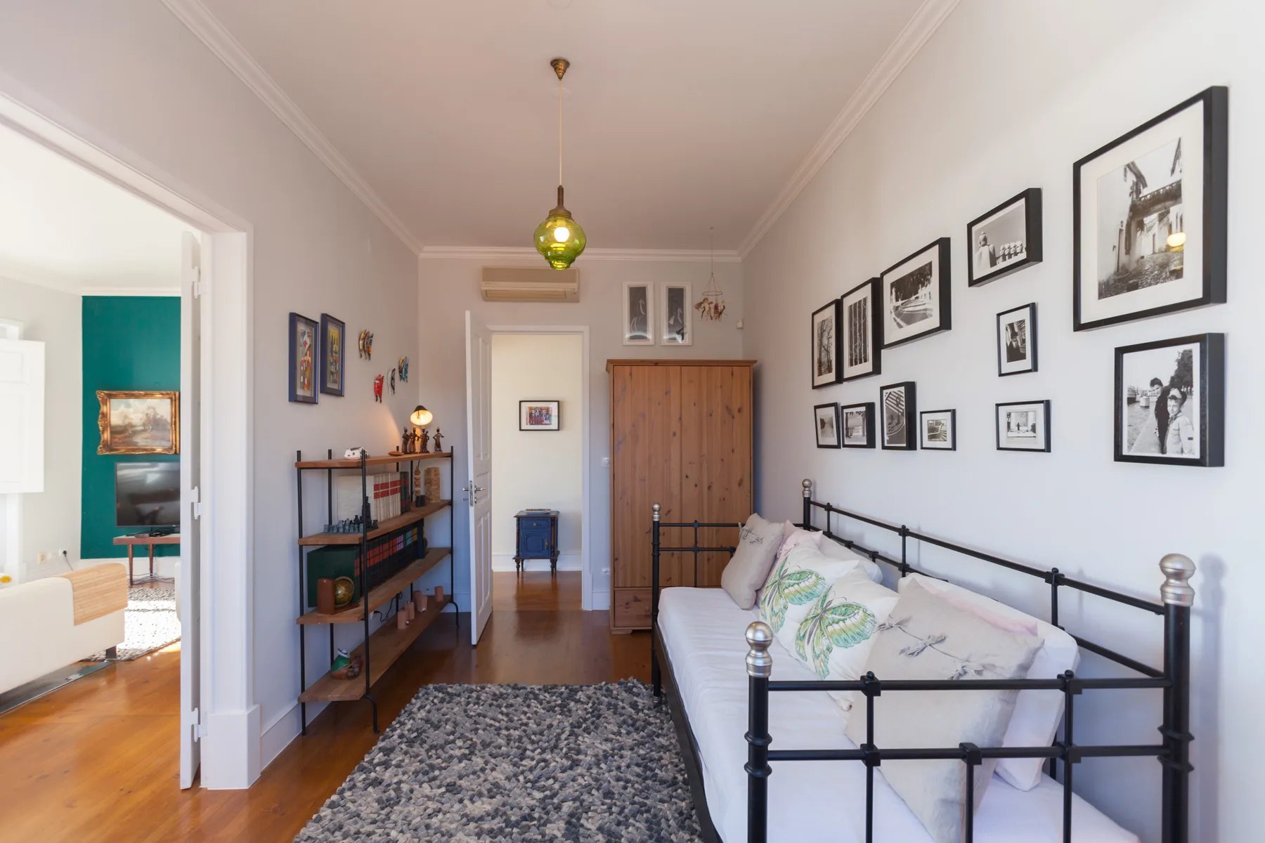 A bright room with a bed, framed pictures, and a wooden wardrobe.
