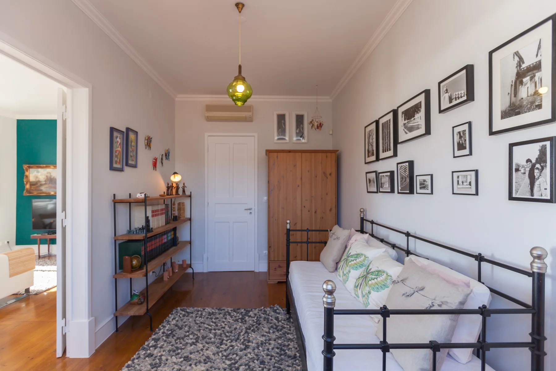 A bright room with a daybed, framed pictures, and a wooden cabinet.