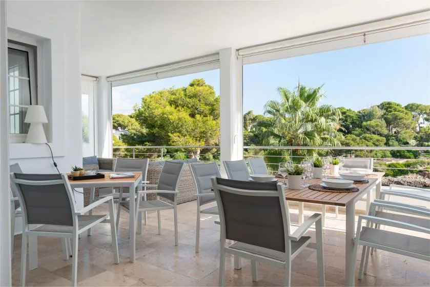 A bright outdoor dining area with tables and seating overlooking leafy trees.