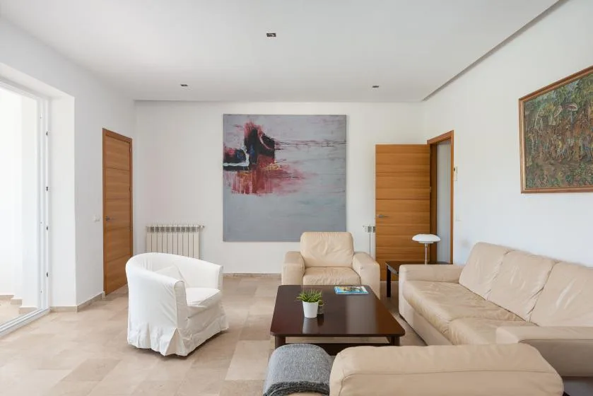 A bright living room with seating arranged around a dark coffee table.