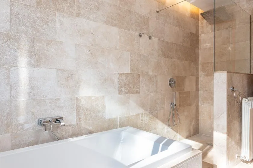 A tiled bathroom with a bathtub and a glass-enclosed shower.