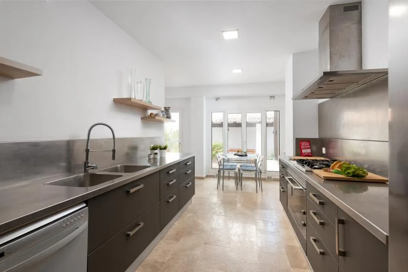 A modern kitchen with dark counters and a dining table by the windows.