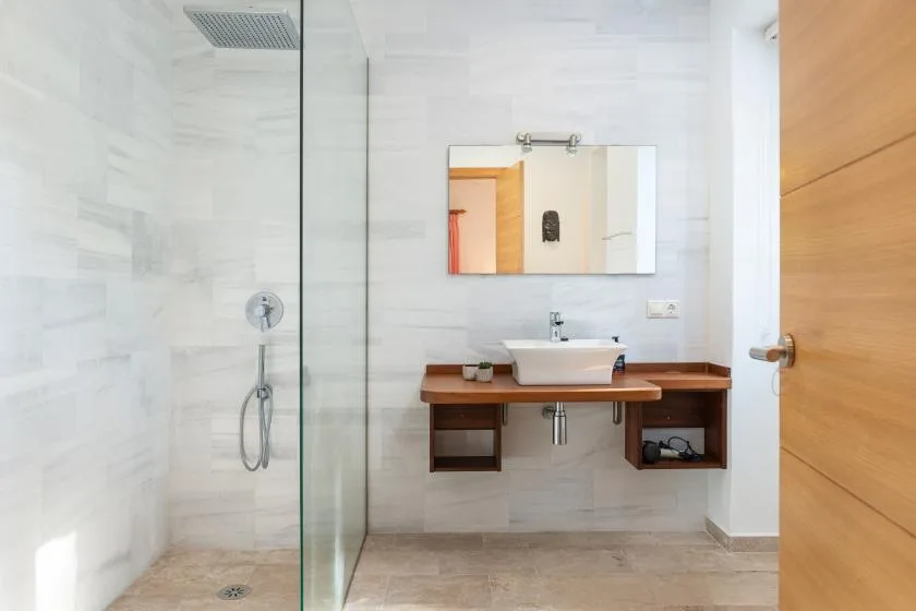 A bright bathroom with a glass shower and a sink on a wooden vanity.