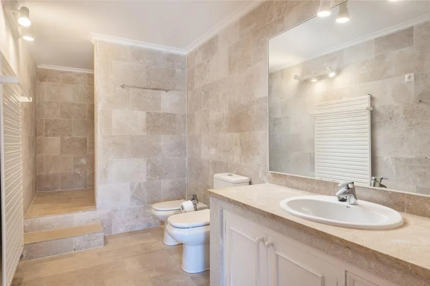 A tiled bathroom with a walk-in shower, toilet, and sink.