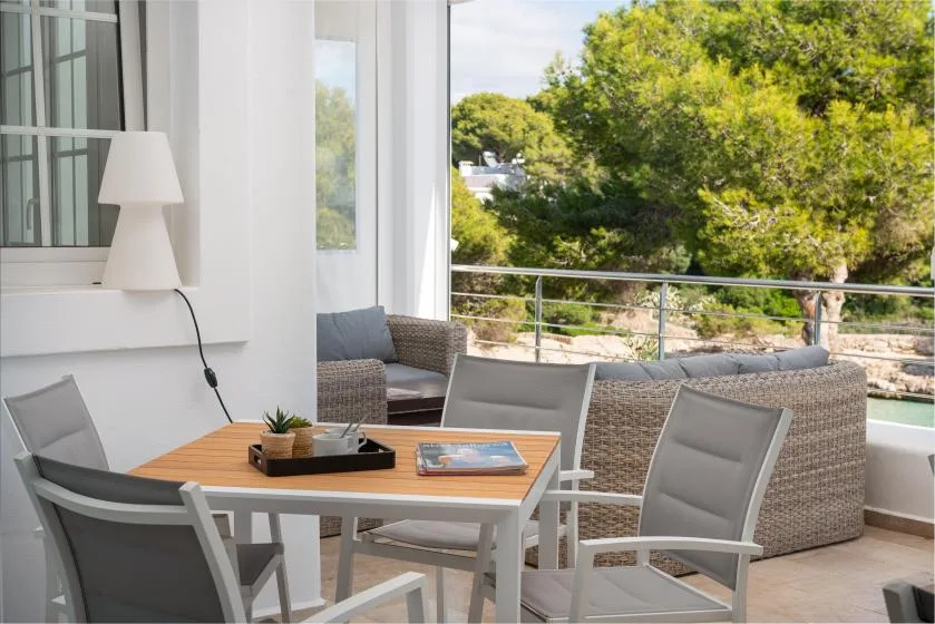 A bright seating area opens onto a terrace with leafy trees beyond.