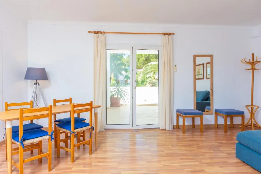 A bright dining and sitting area with a table, chairs, and sliding glass doors.