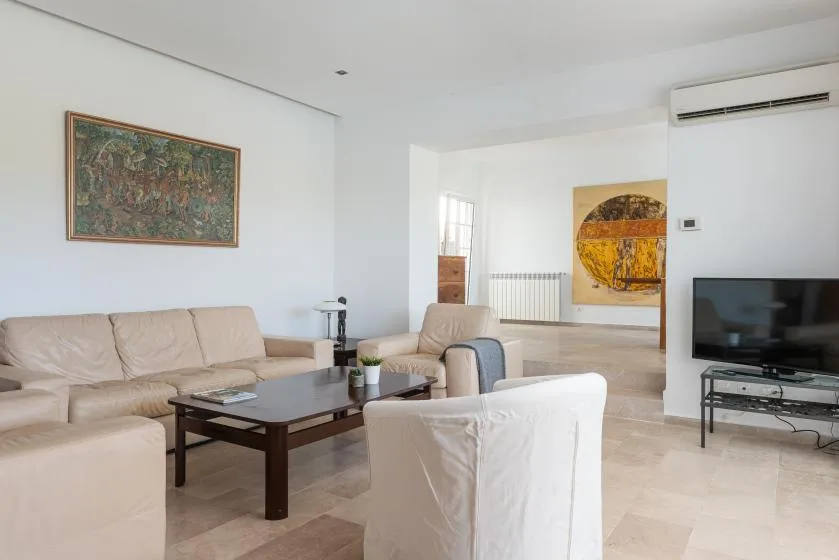 A bright living room with seating, a coffee table, and a television.