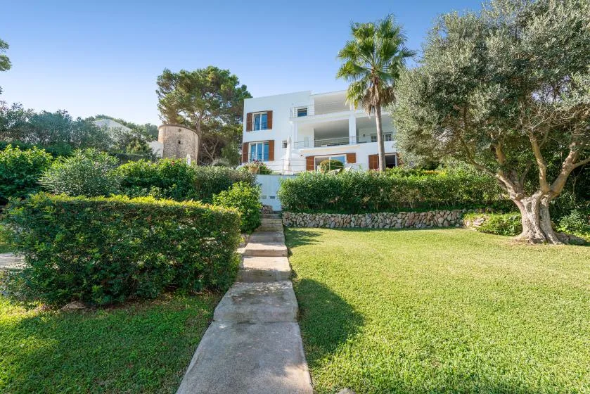 A landscaped garden path leads toward a white multi-story house.