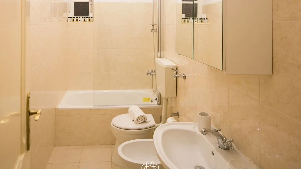 Un baño alicatado con bañera, inodoro y lavabo.