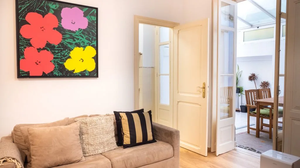 Una sala de estar con un sofá beige y una colorida obra floral.