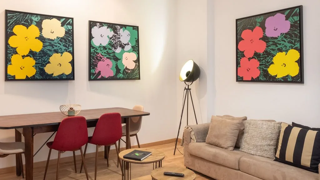 Sala de estar y comedor con sofá, mesa y cuadros coloridos.
